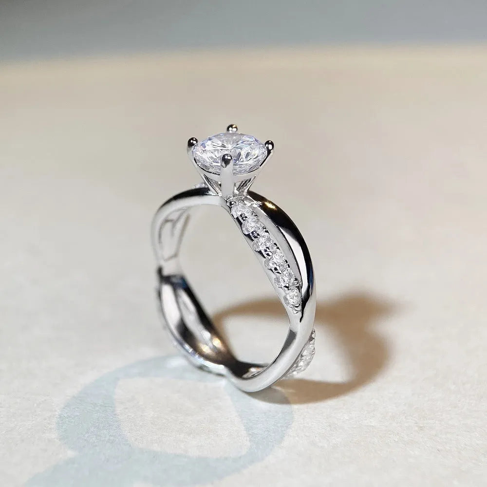Silver geometric cross ring with a 1 karat moissanite stone in a twisted four-claw setting