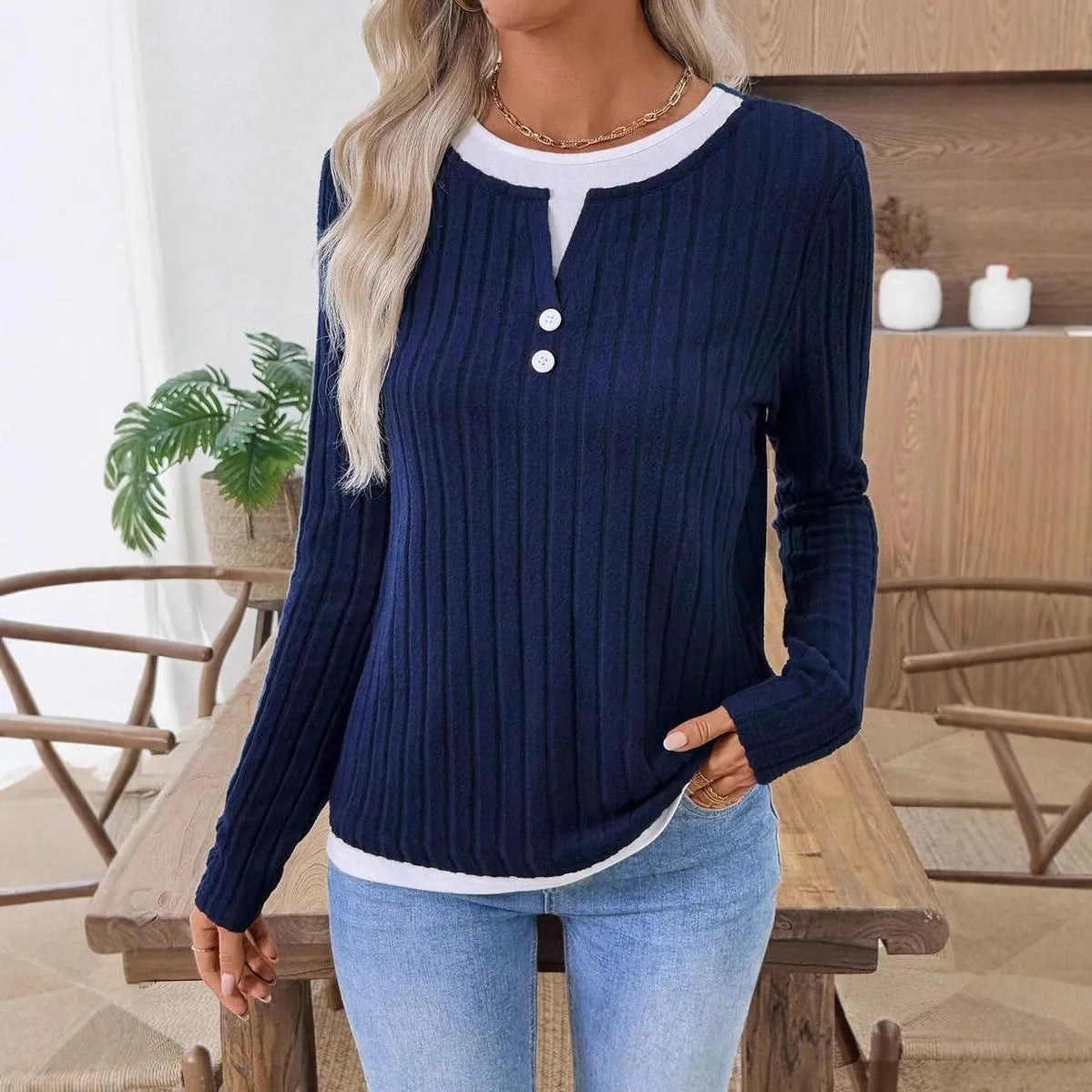 Women's black fake two-piece pullover sweater with round neck button and long sleeves on a model.