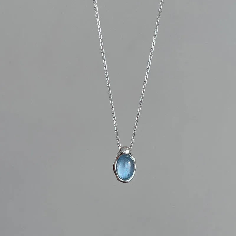 Close-up of a navy blue geometric water drop pendant on a platinum-colour adjustable cross chain necklace.