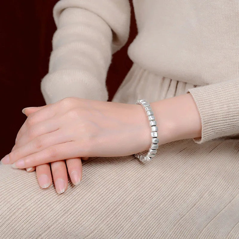Handmade silver bracelet with an irregular square design and wooden details on an elasticated band.