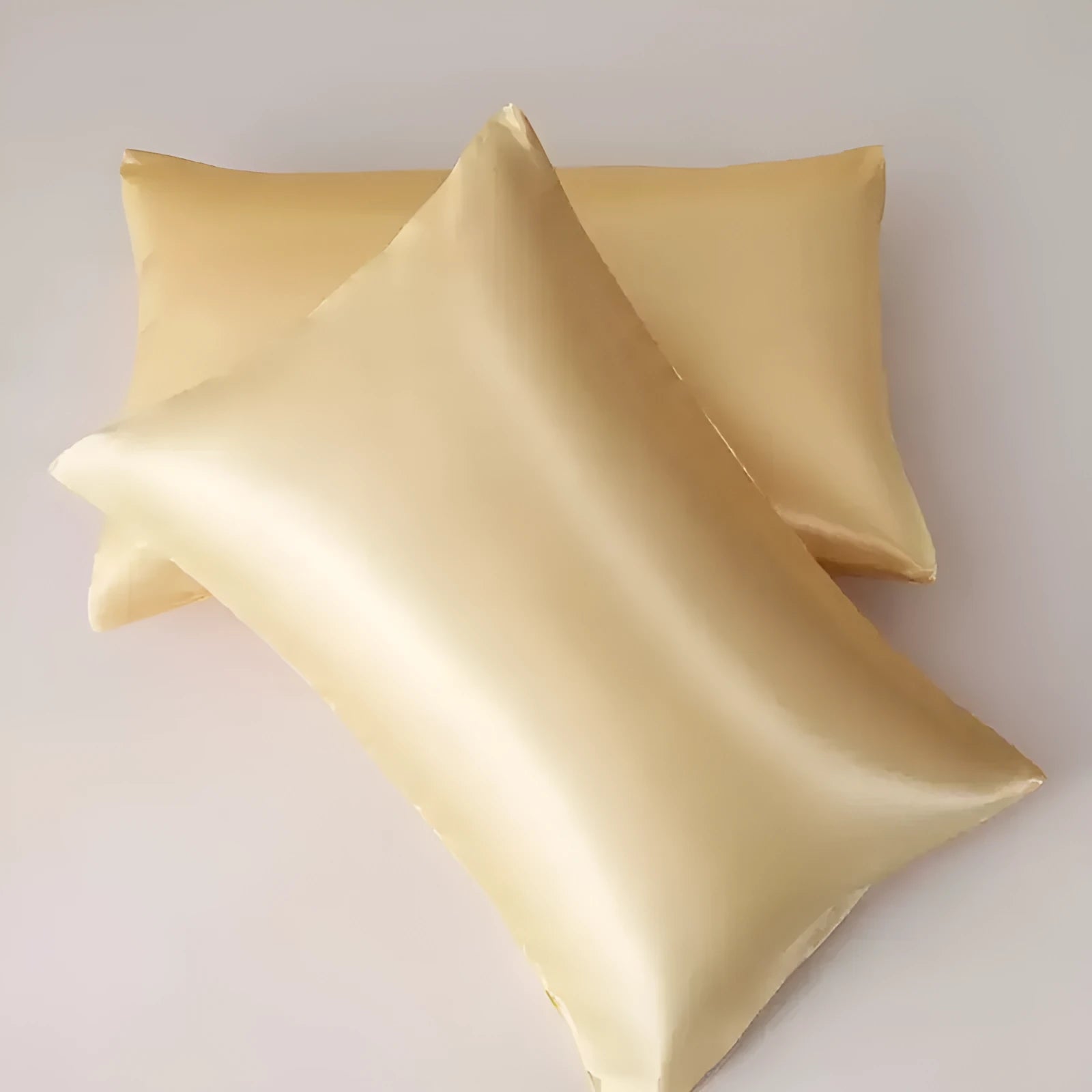 A pair of solid colour satin cloth pillowcases made from polyester plain weave fabric.