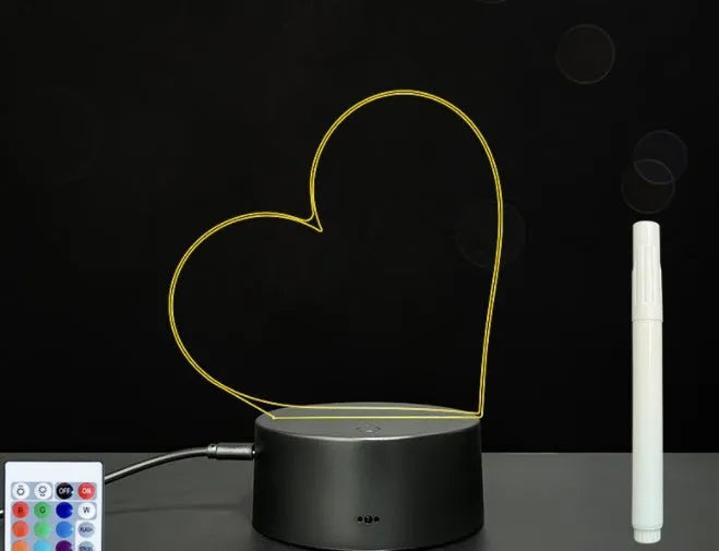 3D acrylic message board night light with remote control and stylus on a desk.
