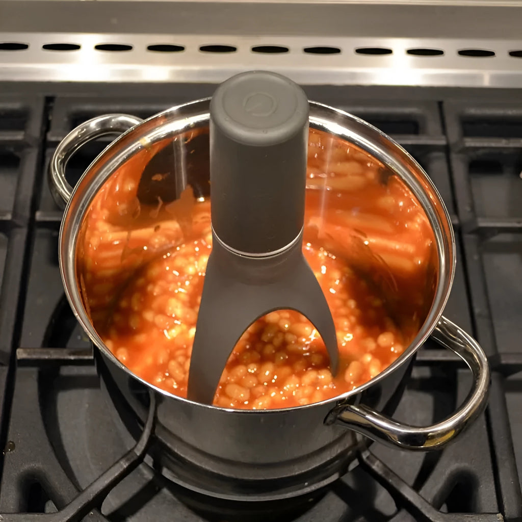 Green Uutensil Stirr automatic cooking mixer device next to a cooking pot.