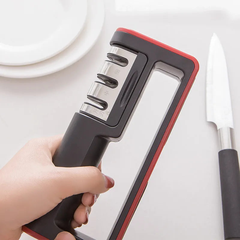 Professional three-stage knife sharpener in black with red trim, showing coarse, ceramic and fine abrasive slots.