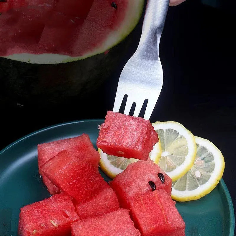 Silver stainless steel watermelon slicer and serving fork with a long handle on a kitchen surface