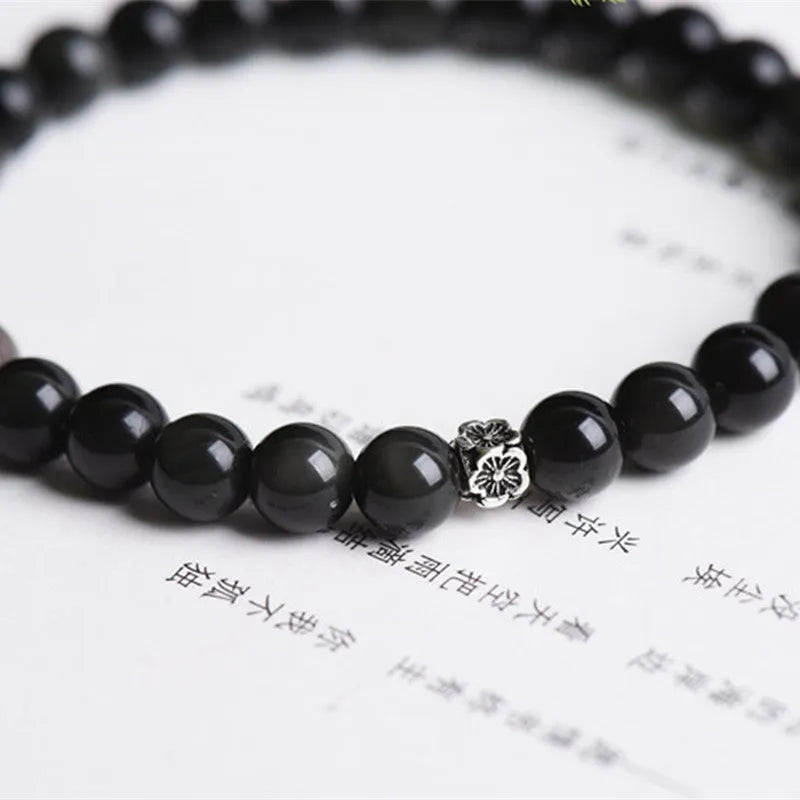 Natural obsidian bracelet with S925 sterling silver flower accessories on a wrist