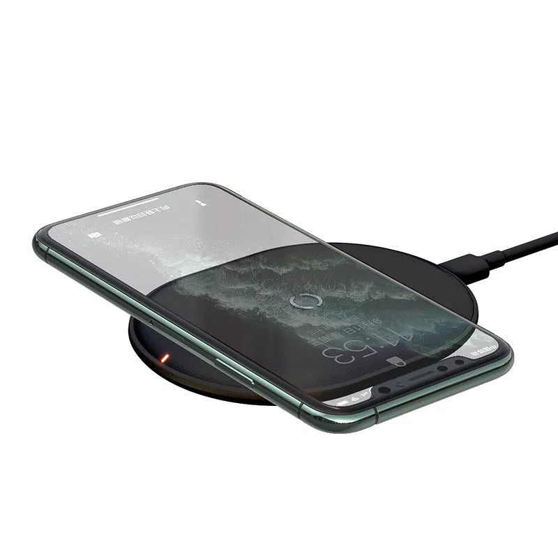 Baseus Rough 15W wireless charging pad in black on a desk next to a mobile phone.