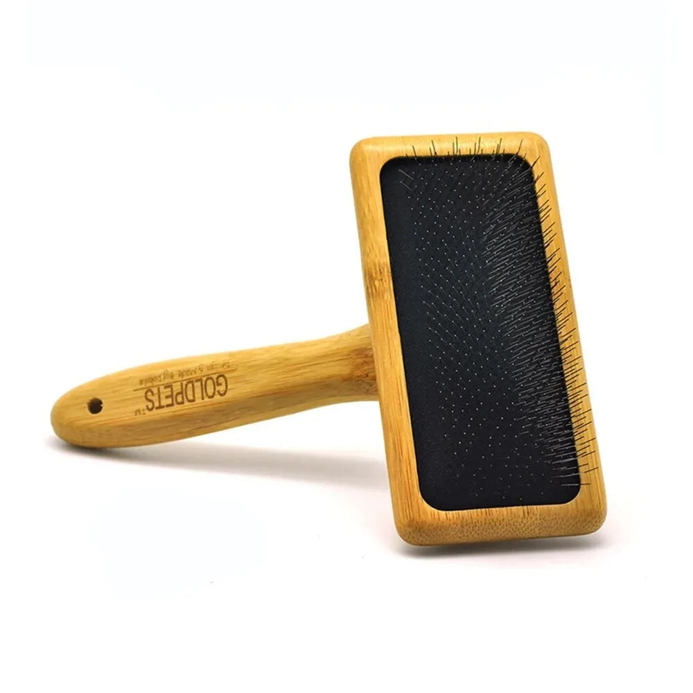 Goldpets bamboo and wood pet slicker brush with stainless steel pins on a wooden table.
