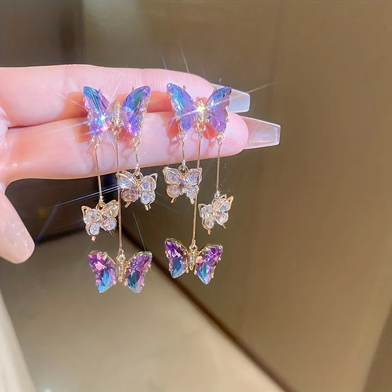 A pair of silver and blue purple butterfly tassel earrings with crystal flowers and droplet pendants.