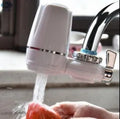 White plastic faucet water purifier with ceramic filter cartridge mounted on kitchen tap