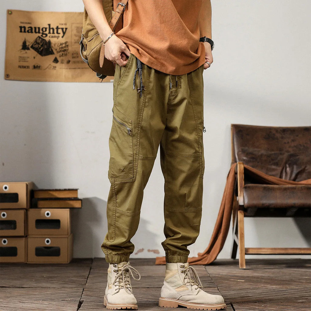 Man wearing khaki loose-fit cotton harem pants with tapered ankle-banded legs.