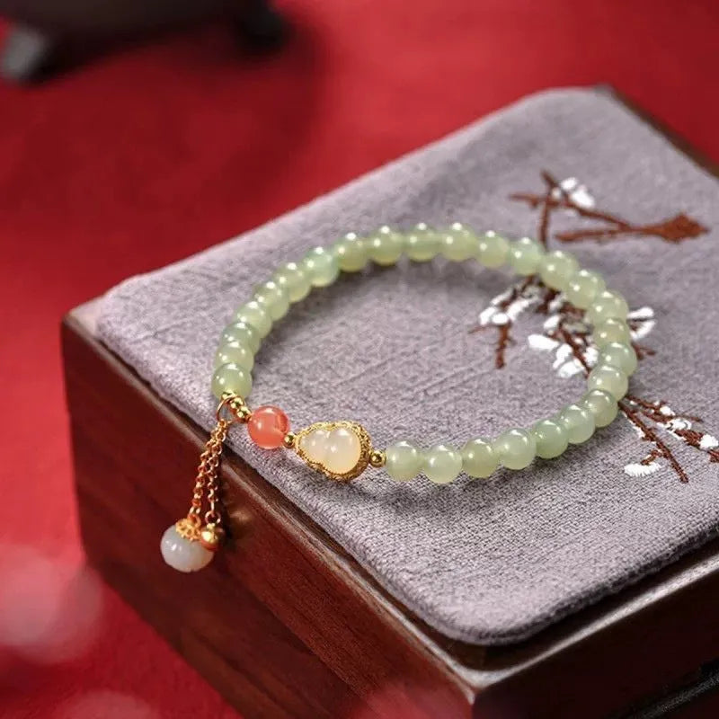 Natural jade bracelet with a gold-plated gourd charm and fu character charm.