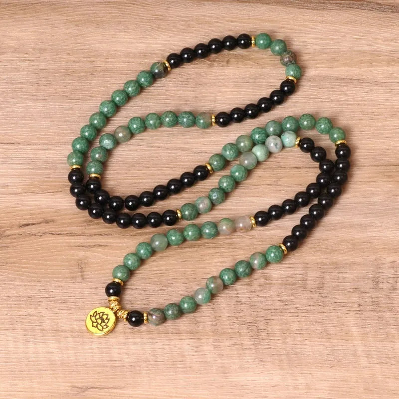 Green and black alloy bead elastic bracelet on a wrist.