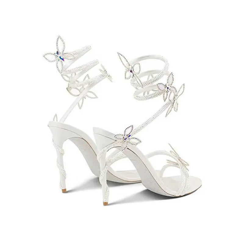 Snake butterfly rhinestone flower stiletto heel Roman sandals in gold with round toe and buckle closure