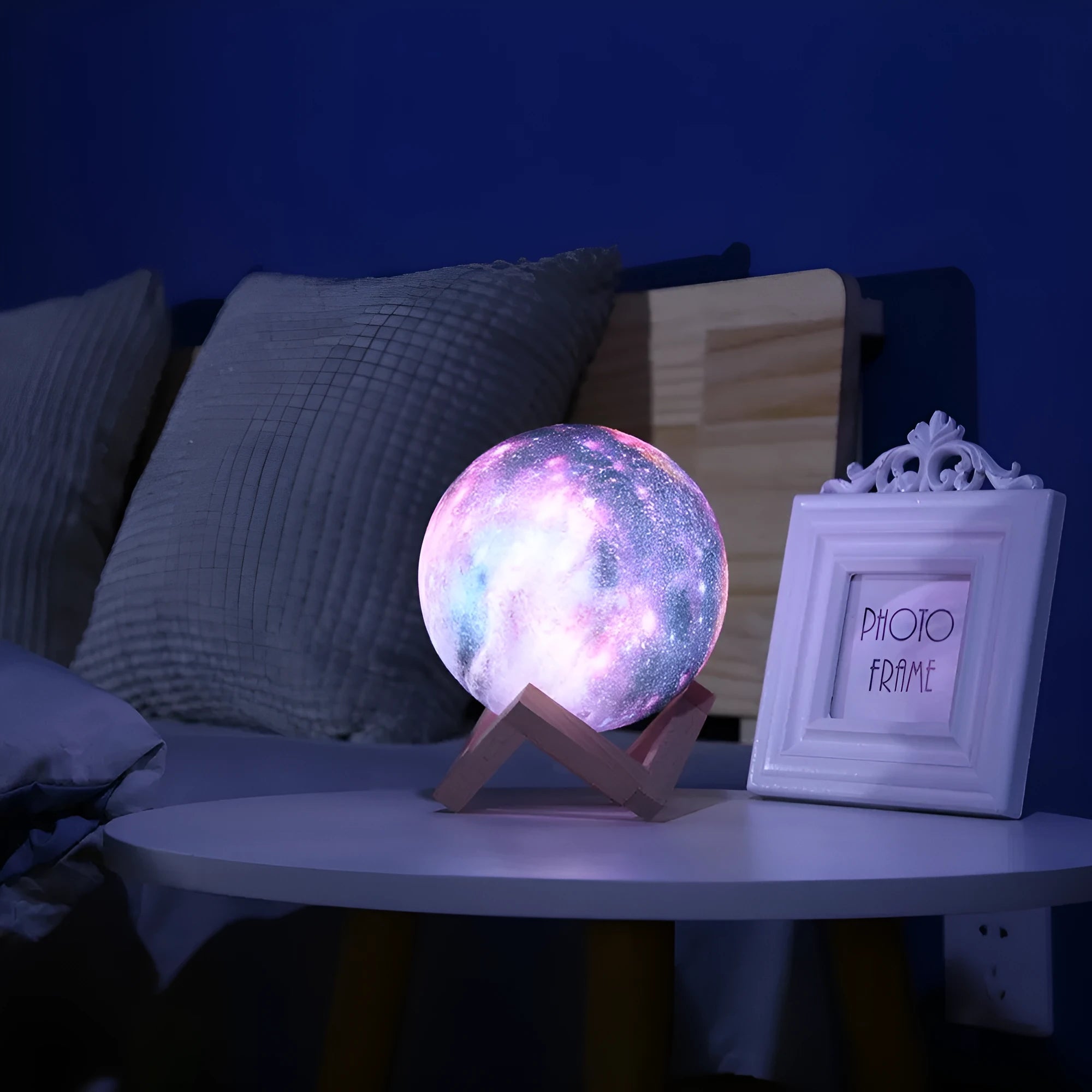 3D-printed white lunar sphere night light with crater texture on a dark surface.