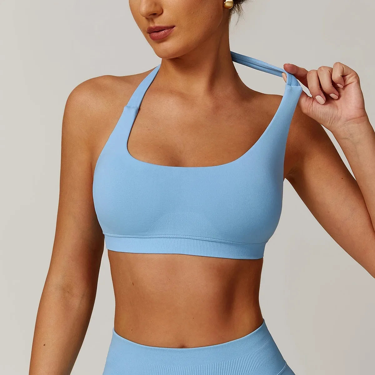 Women's black halter neck sports bra with removable pads on a mannequin.