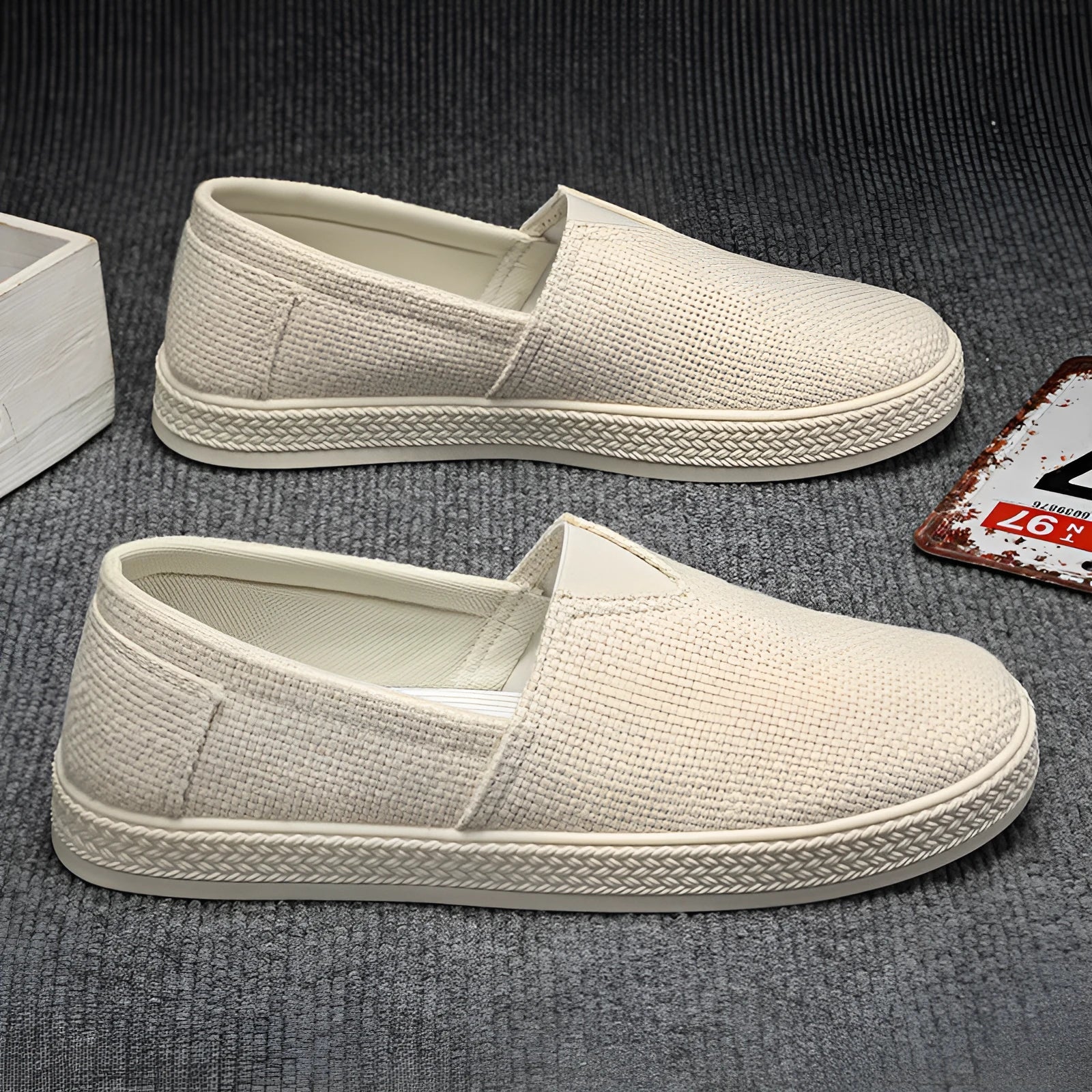 Men's beige canvas slip-on loafers with a round toe and shallow cut on a plain background.