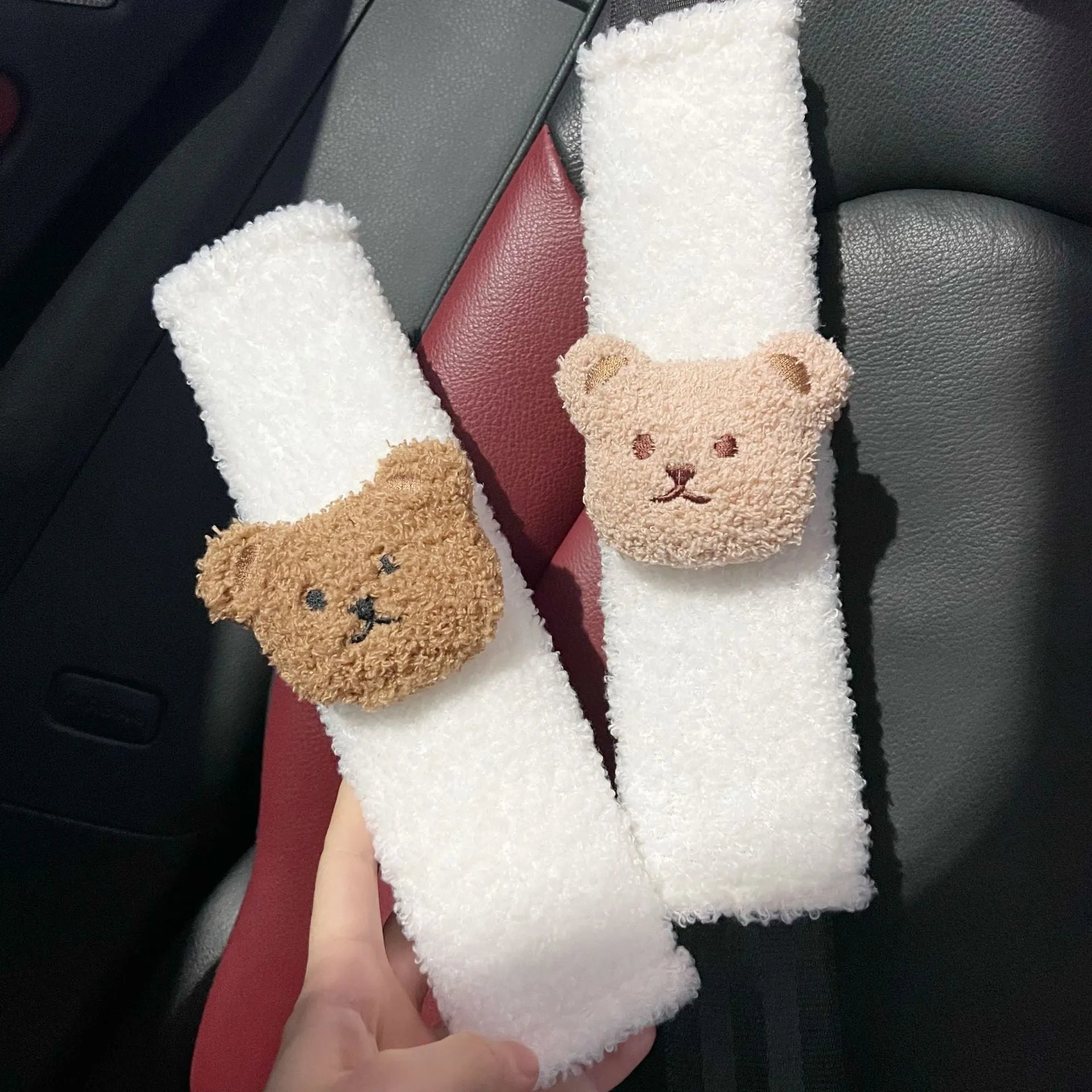 Close-up of a khaki-coloured plush bear seat belt cover on a car seat strap.