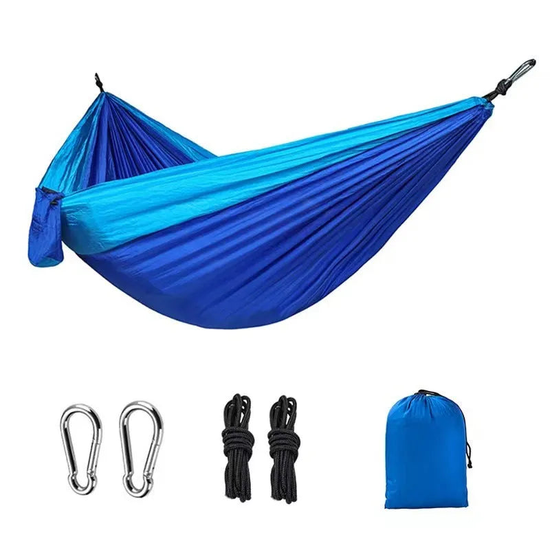 Blue parachute nylon outdoor hammock hung between two trees in a garden setting