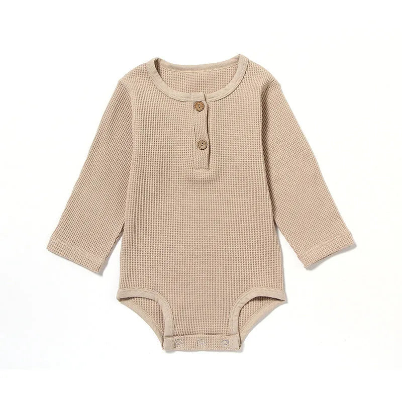 Neutral baby romper in waffle cotton fabric with long sleeves, shown in beige with cotton rope detail.