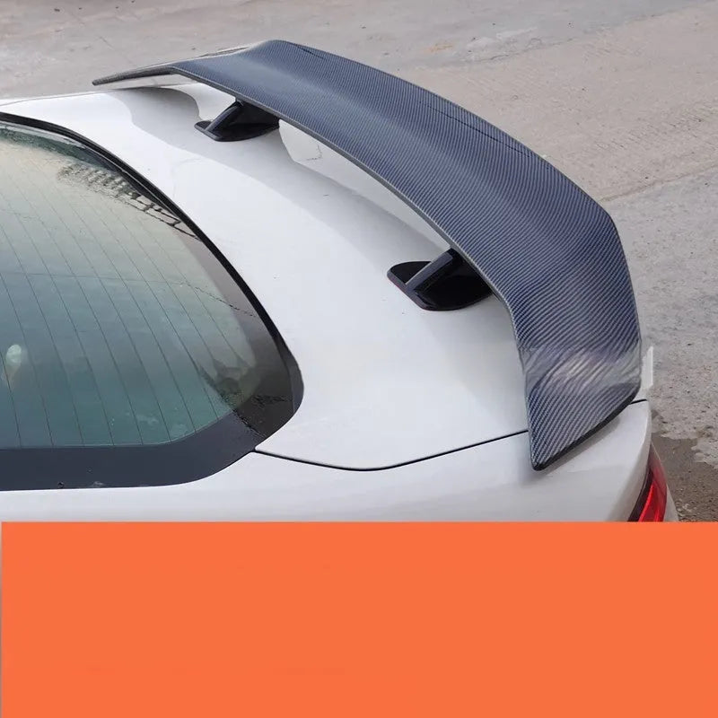 A universal punch-free ABS plastic car tail wing spoiler showing bright black, white, and carbon pattern finish options.