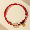 Handmade bracelet with Hetian jade peace buckle charm on adjustable braided rope.