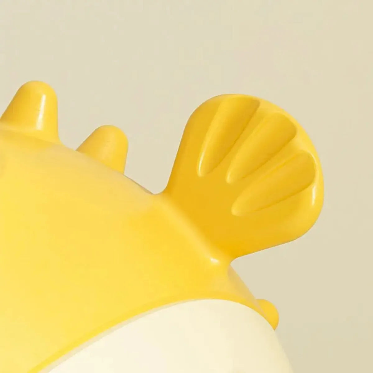 Yellow vinyl fish-shaped squeaky dog chew toy on a plain background