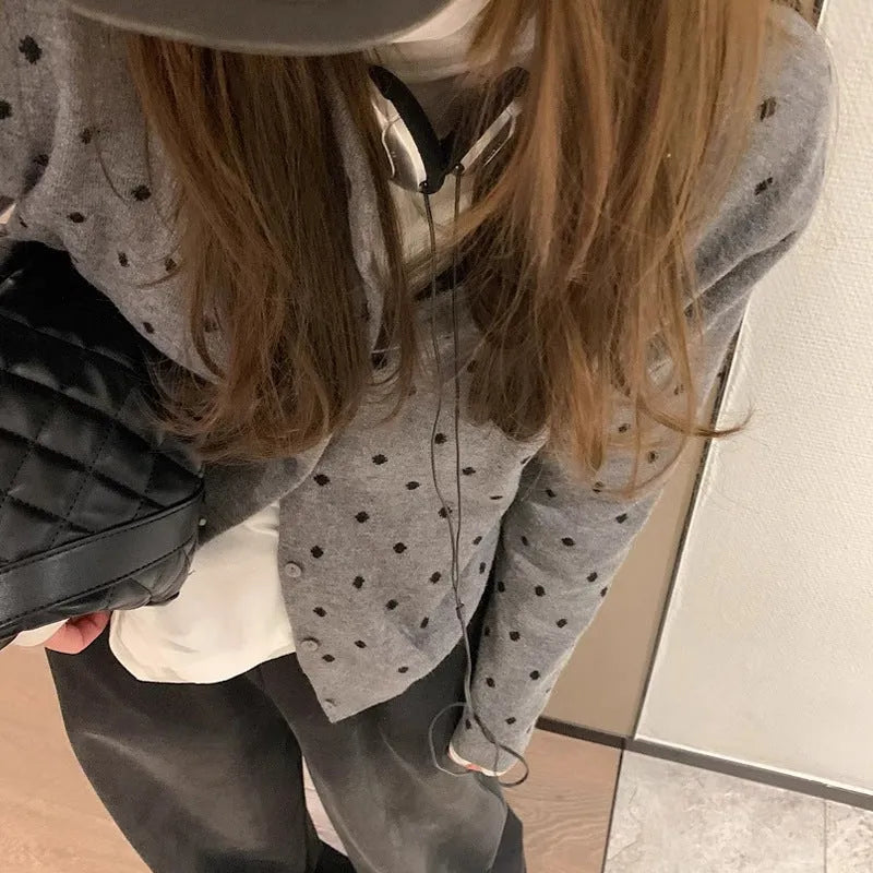 Women's grey dot pattern knitted cardigan with crochet floral detail on the front.