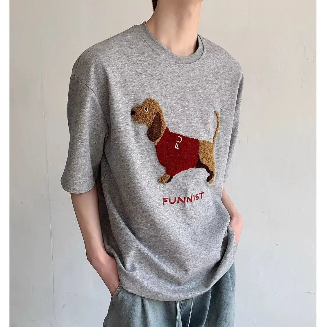 Men's grey cotton T-shirt with an embroidered sausage dog on the chest, showing short sleeves and a round neck.