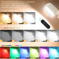 Modern white plastic magnetic wall lamp with a remote control on a wooden surface.