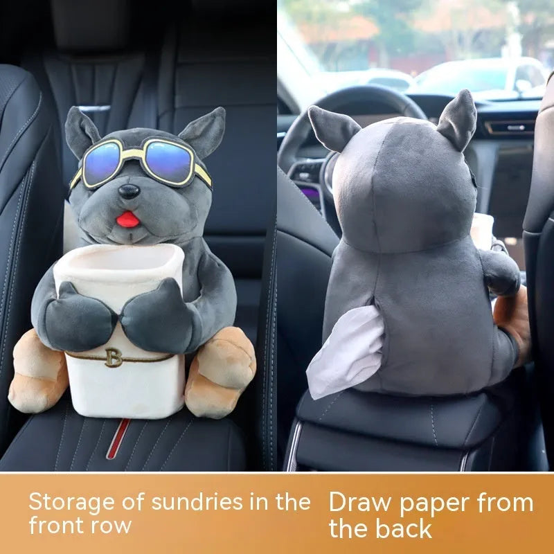 Plush car tissue box holder hanging from flip-down armrest with humorous dog design