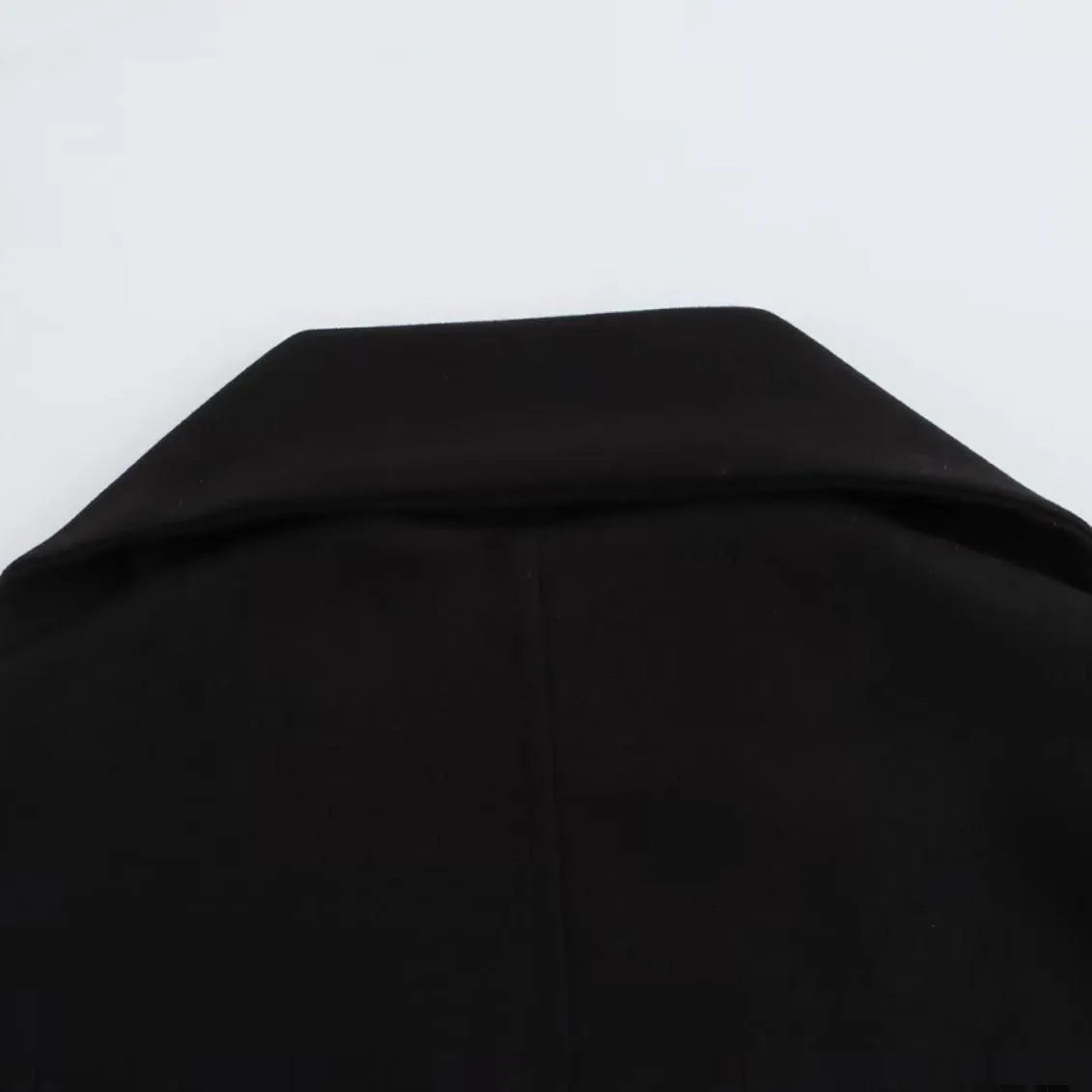 A woman wearing a longline black polyester coat with a detachable faux fur collar.