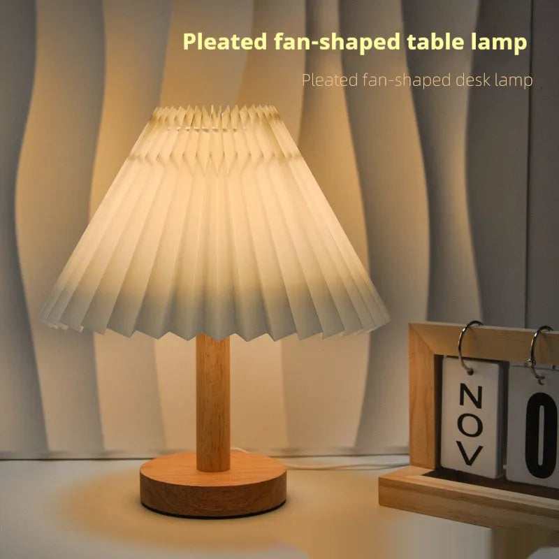 Vintage red pleated umbrella-shaped bedside lamp with remote control on a wooden nightstand.
