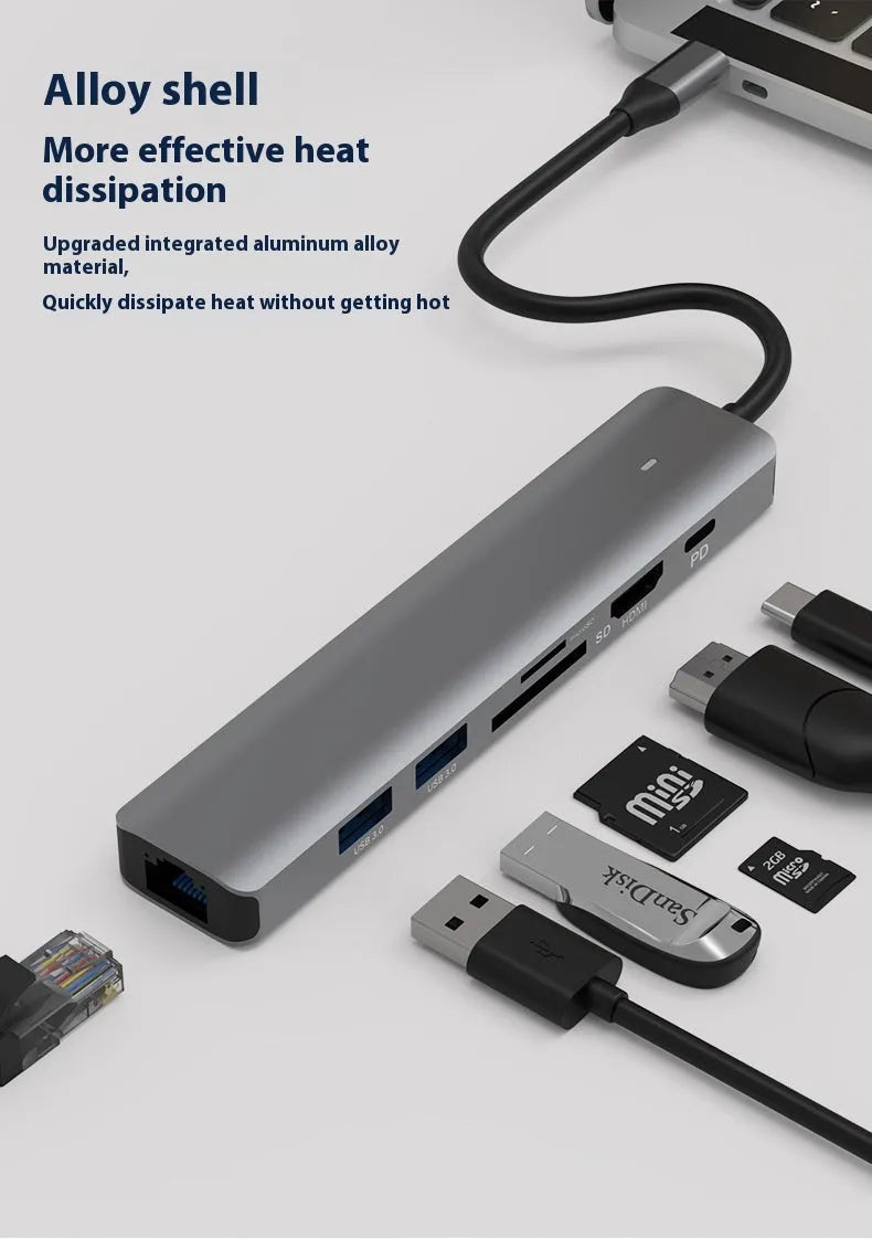 Silver aluminium 7-in-1 USB hub with SD card slot, microSD slot, USB-C PD port, and multiple USB-A ports.