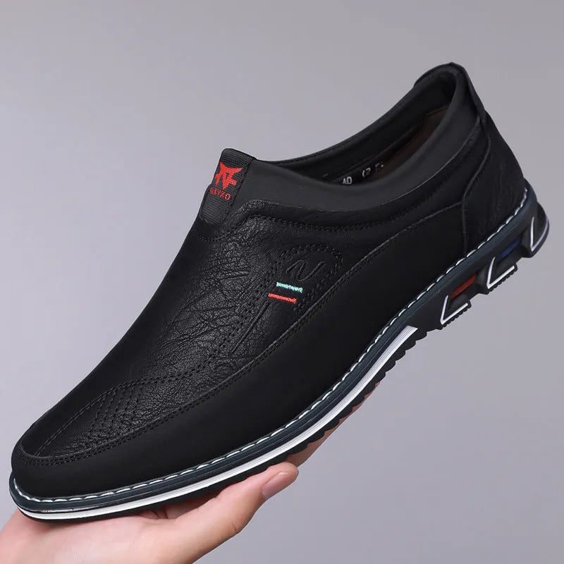 Men's black leather-toe casual shoes with fabric upper and rubber sole on a plain background.