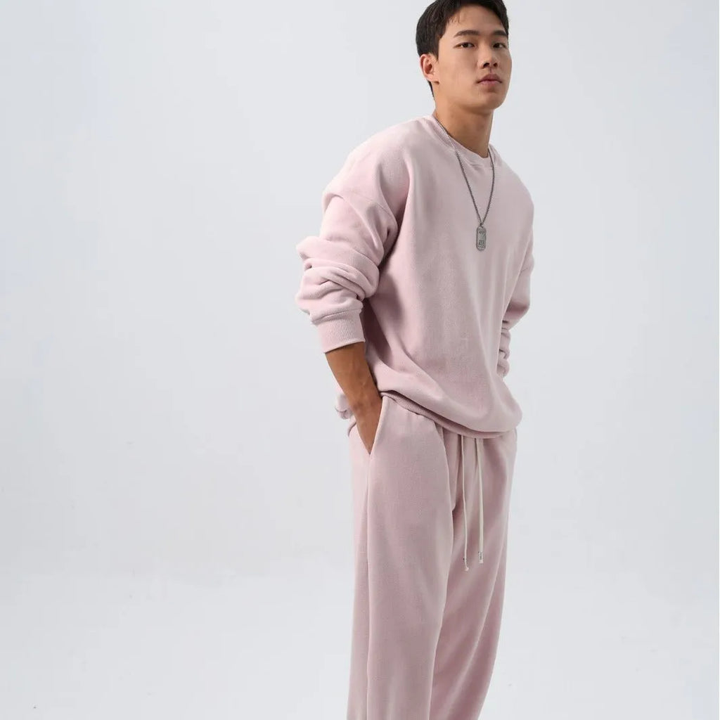 Men's black loose fit polar fleece winter sports suit with long sleeve coat and trousers on a hanger.