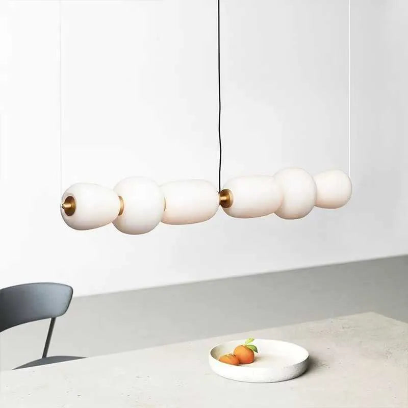 Modern minimalist long chandelier with iron frame and glass elements emitting warm LED light in a living room