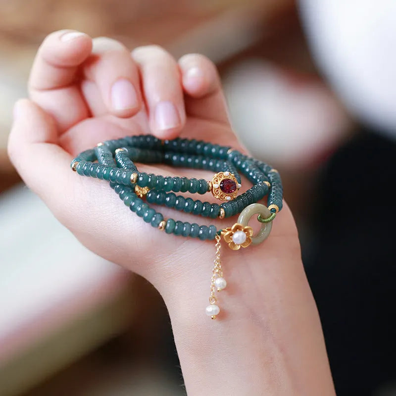 Close-up of a blue water jade and abacus bead bracelet with tourmaline rings and freshwater pearls.