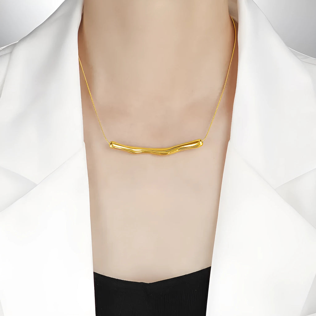 Close-up of a women's titanium steel necklace with an irregular pleated textured pendant in a gold tone.