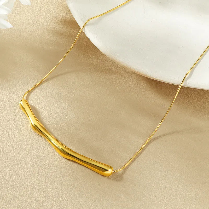 Close-up of a women's titanium steel necklace with an irregular pleated textured pendant in a gold tone.