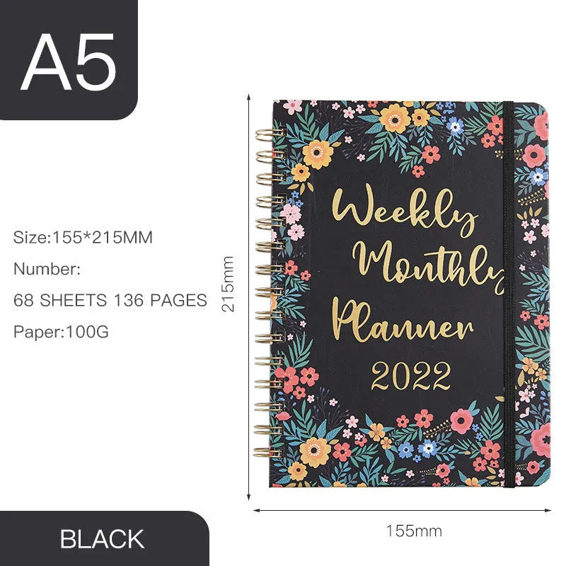 A5 spiral notebook open on a desk showing one of ten available artistic cover designs.
