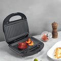 Black double-sided electric sandwich pan with brushed stainless steel lid and six removable non-stick plates.