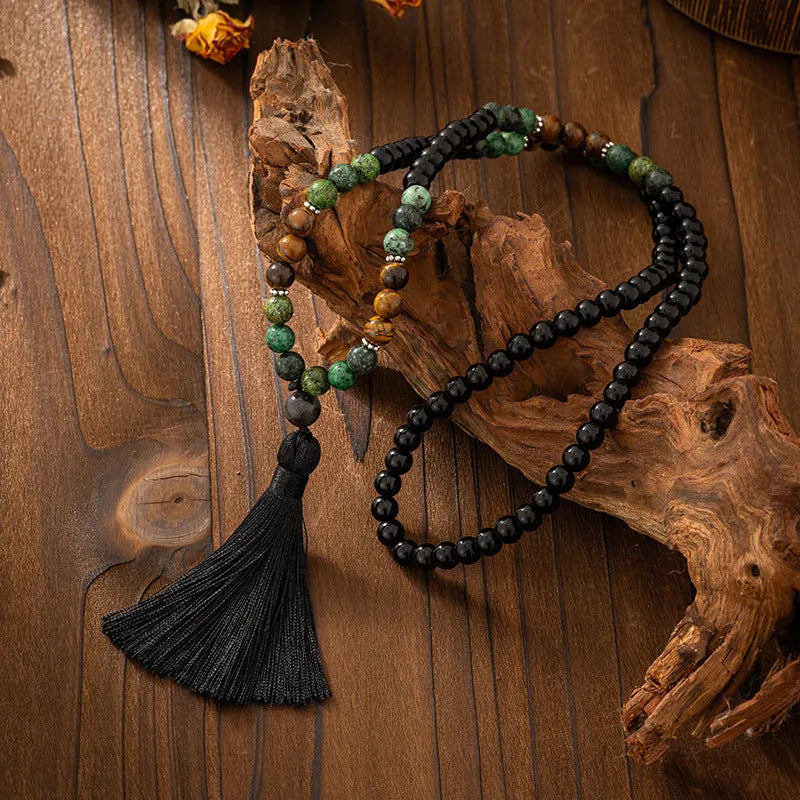 Vintage bohemian style long necklace with natural stone beads, geometric chain, tassel, and matching bracelet on a grey background.