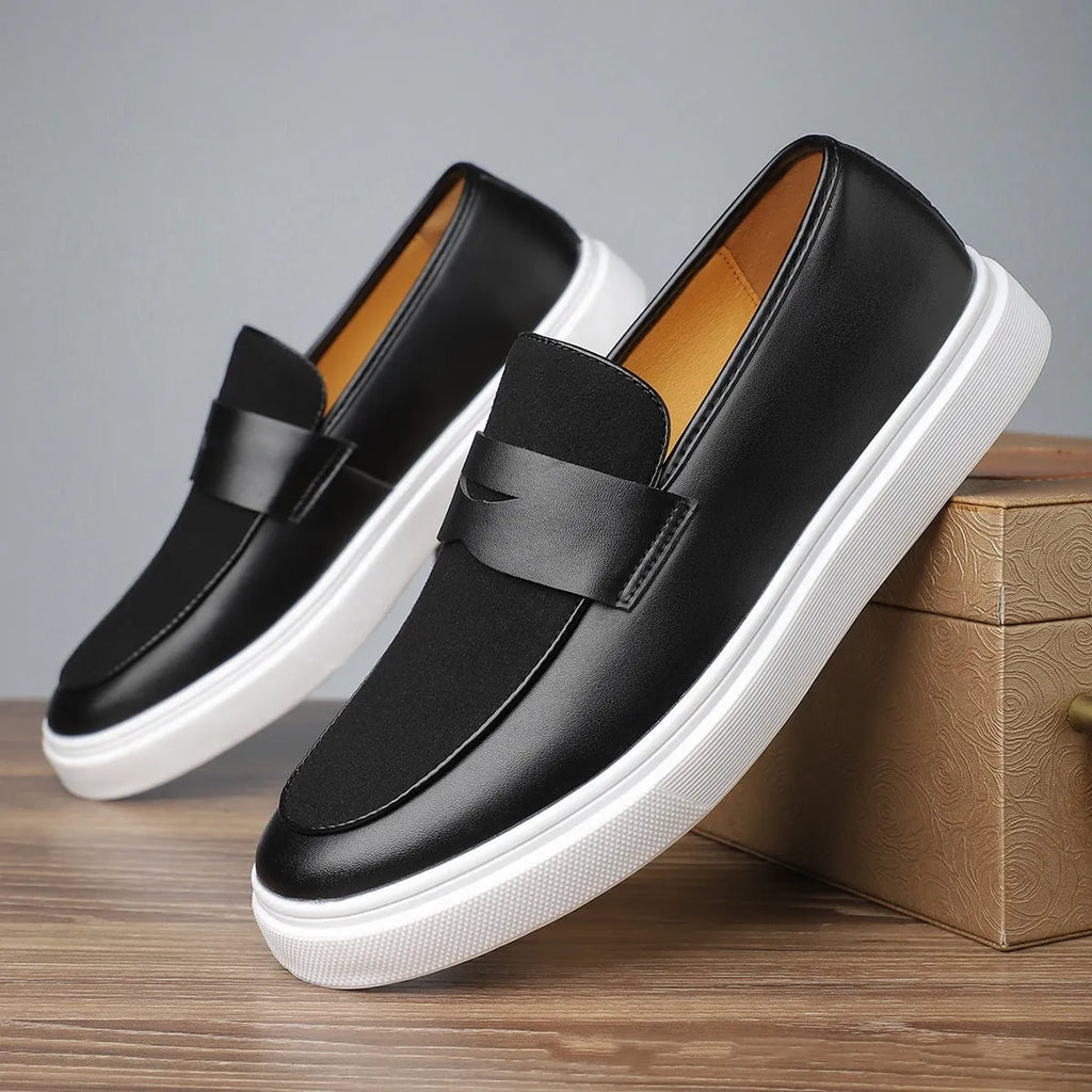 Black men's slip-on loafers with tassel detail and rubber sole, shown in profile view
