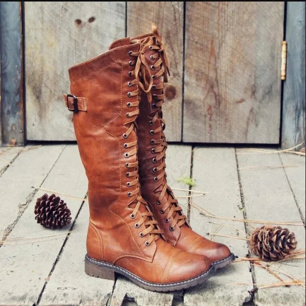 Women's black artificial PU leather knight boots with a cross-strap design, shown from the side.