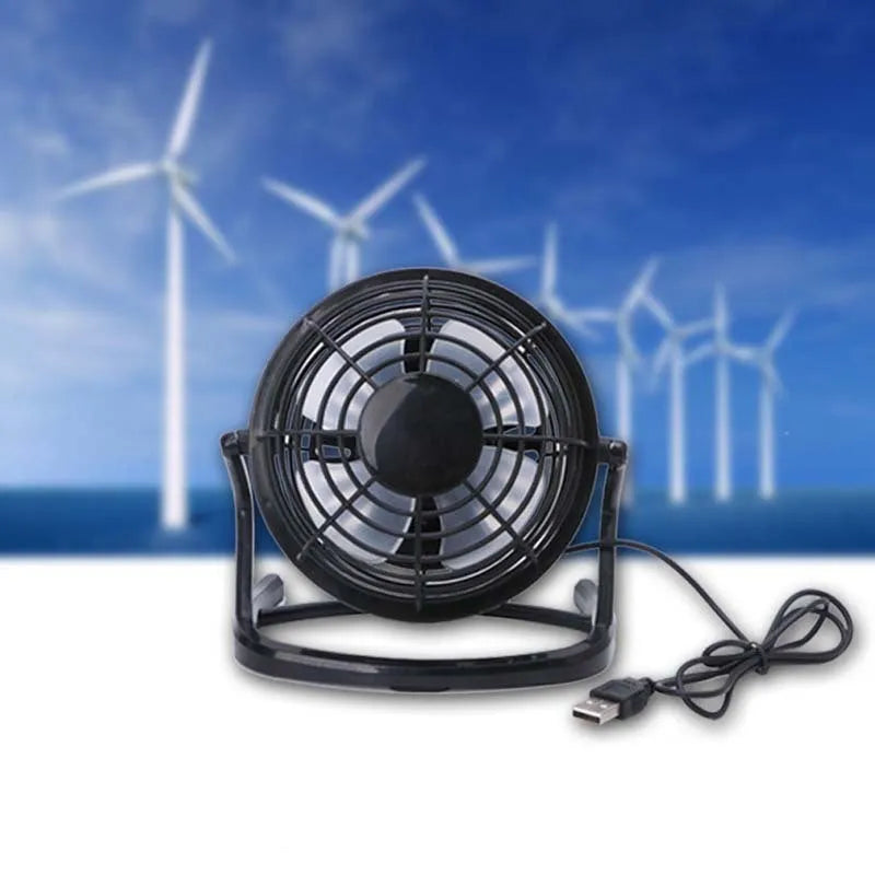 Mini black USB desk fan with adjustable tilt, shown on a desk next to a laptop.