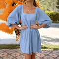 A light blue children's backless dress with a square collar, puff sleeves, and an A-line skirt on a hanger.
