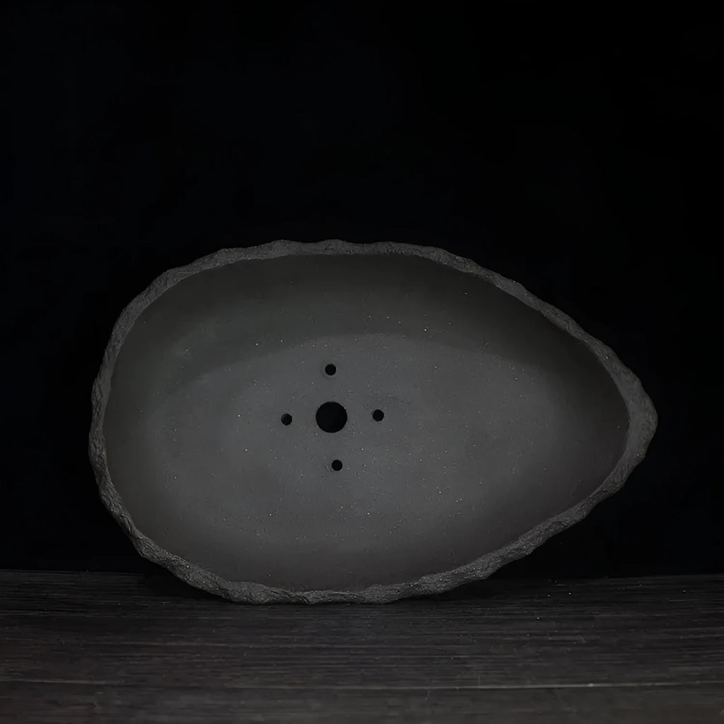 Handmade purple clay flower pot in a unique shape, shown as a floor-standing planter for indoor plants.