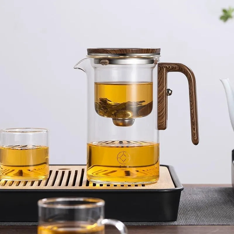 Glass teapot with wooden handle showing magnetic tea separation button and detachable inner infuser.