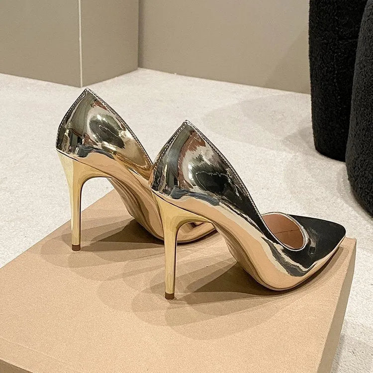 Gold metallic women's pointed toe slip-on pump with a tall stiletto heel on a white background.